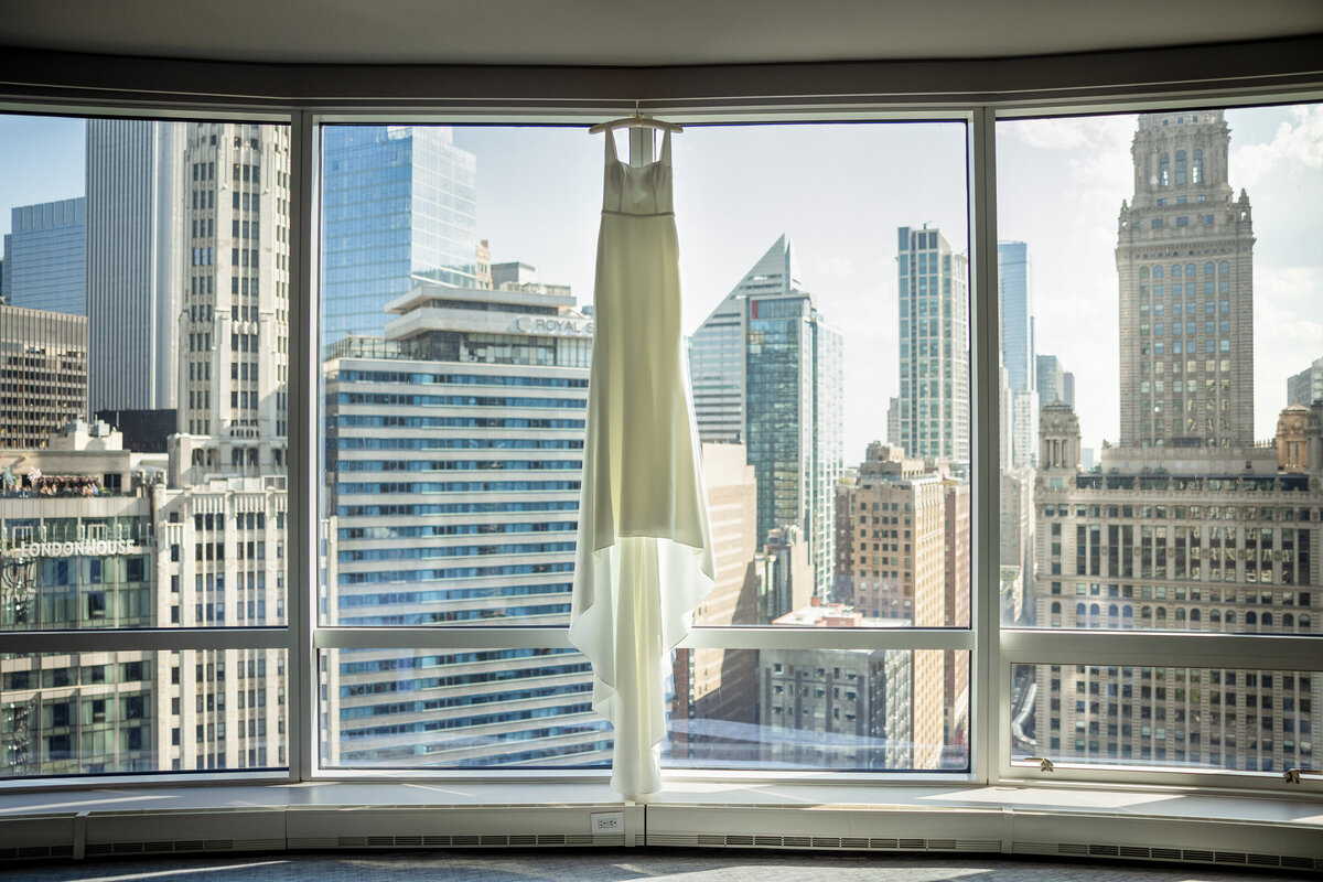 Floor to ceiling windows behind the "made with love" elegant white "hunter"  wedding dress with square neck at Trump suit