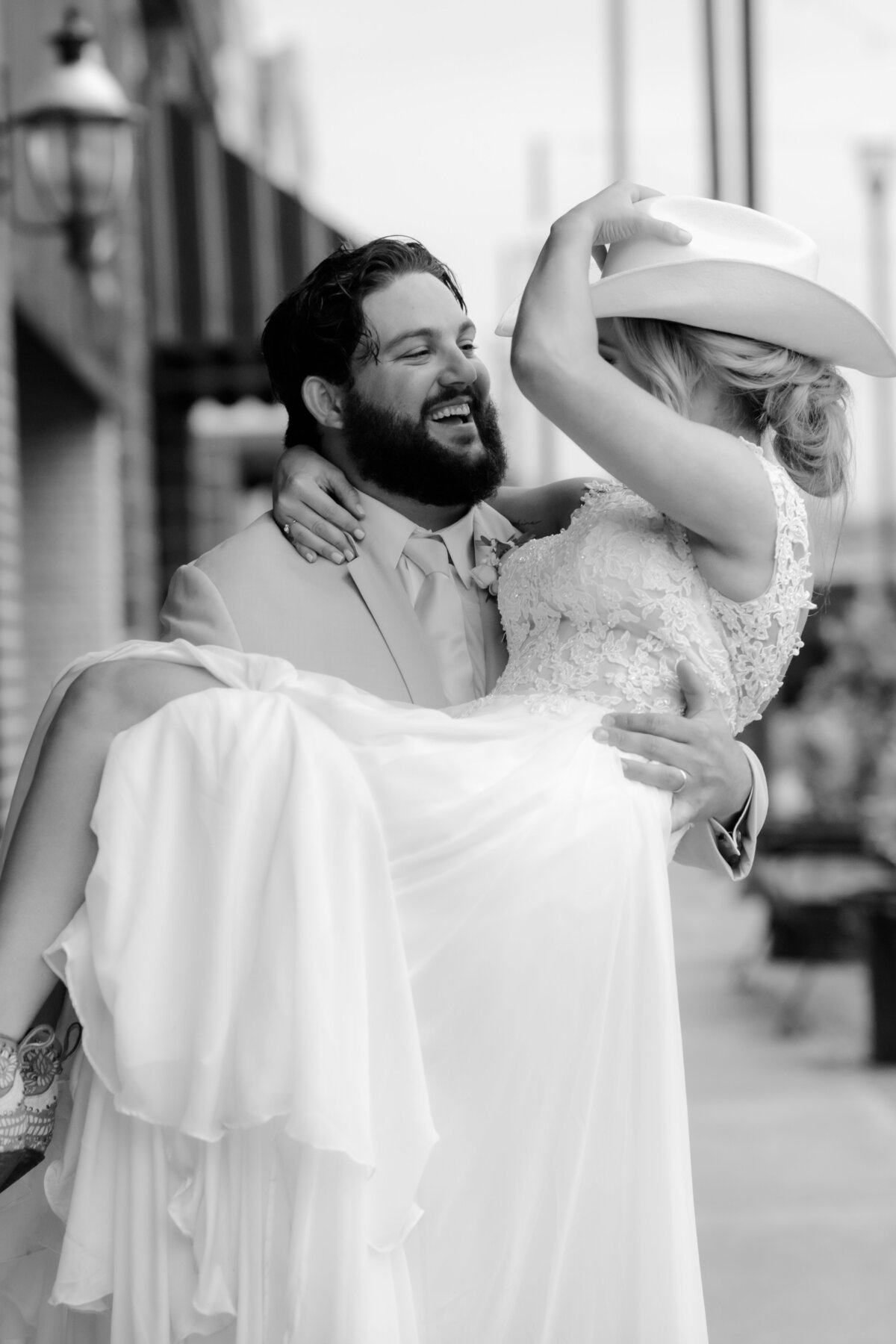 Little Rock wedding photographer captures groom laughing as he holds his bride in his arms for their downtown bridal session