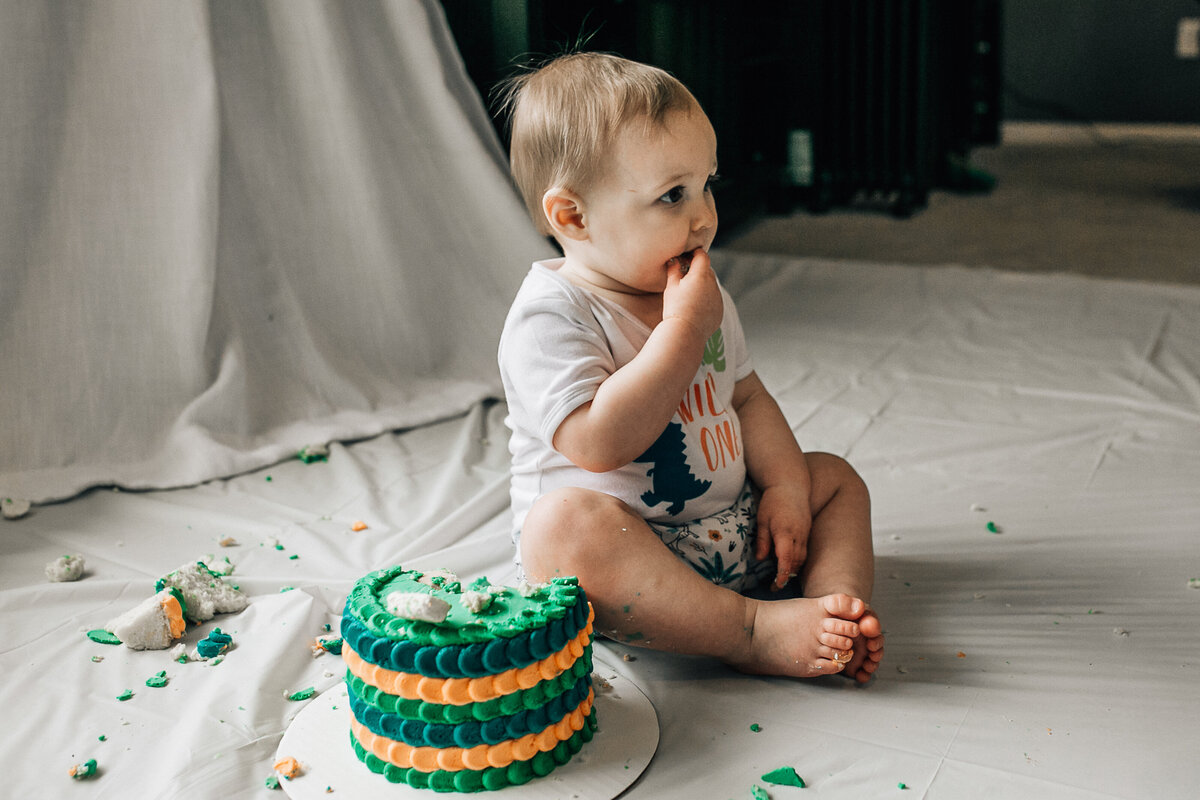 Baby sits on the floor with cake.