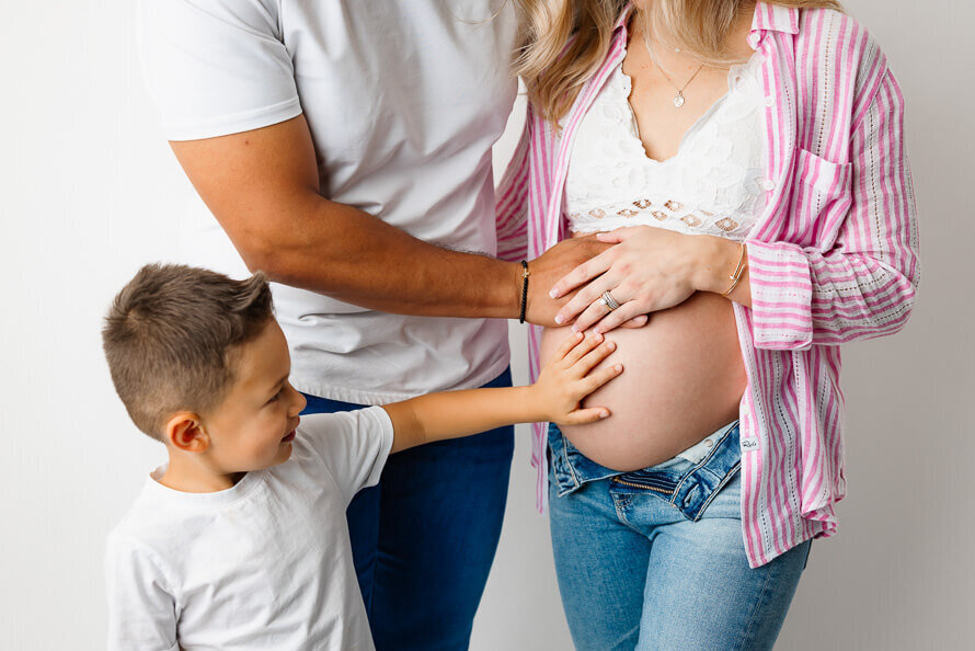 Close up of a boy touching his moms pregnant stomach.