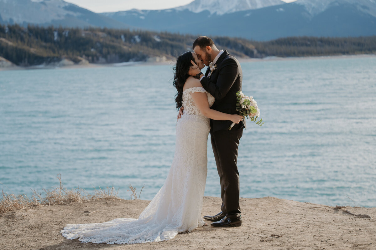 Couples elopement photo kissing on the beach in front of a lake
