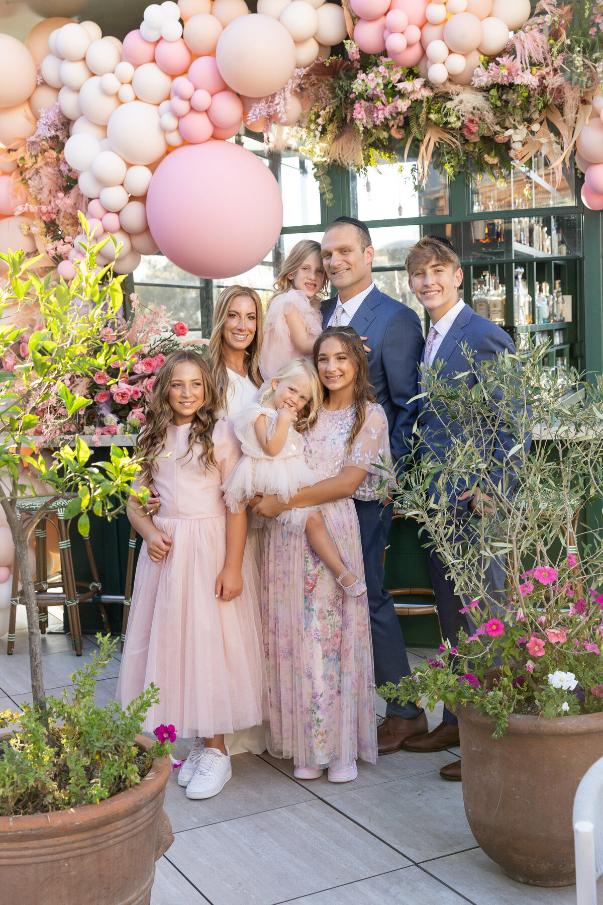 A family smiling together under a balloon arch