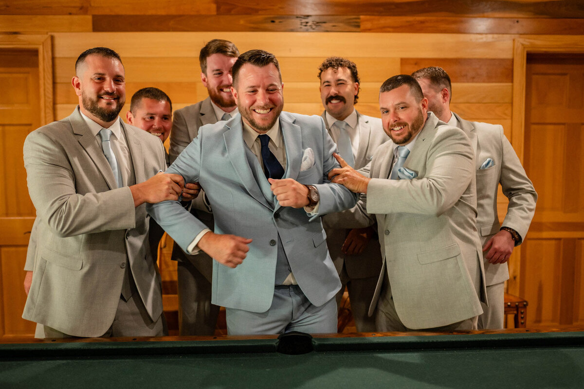 Groom cheered by his groomsmen in front for pool table