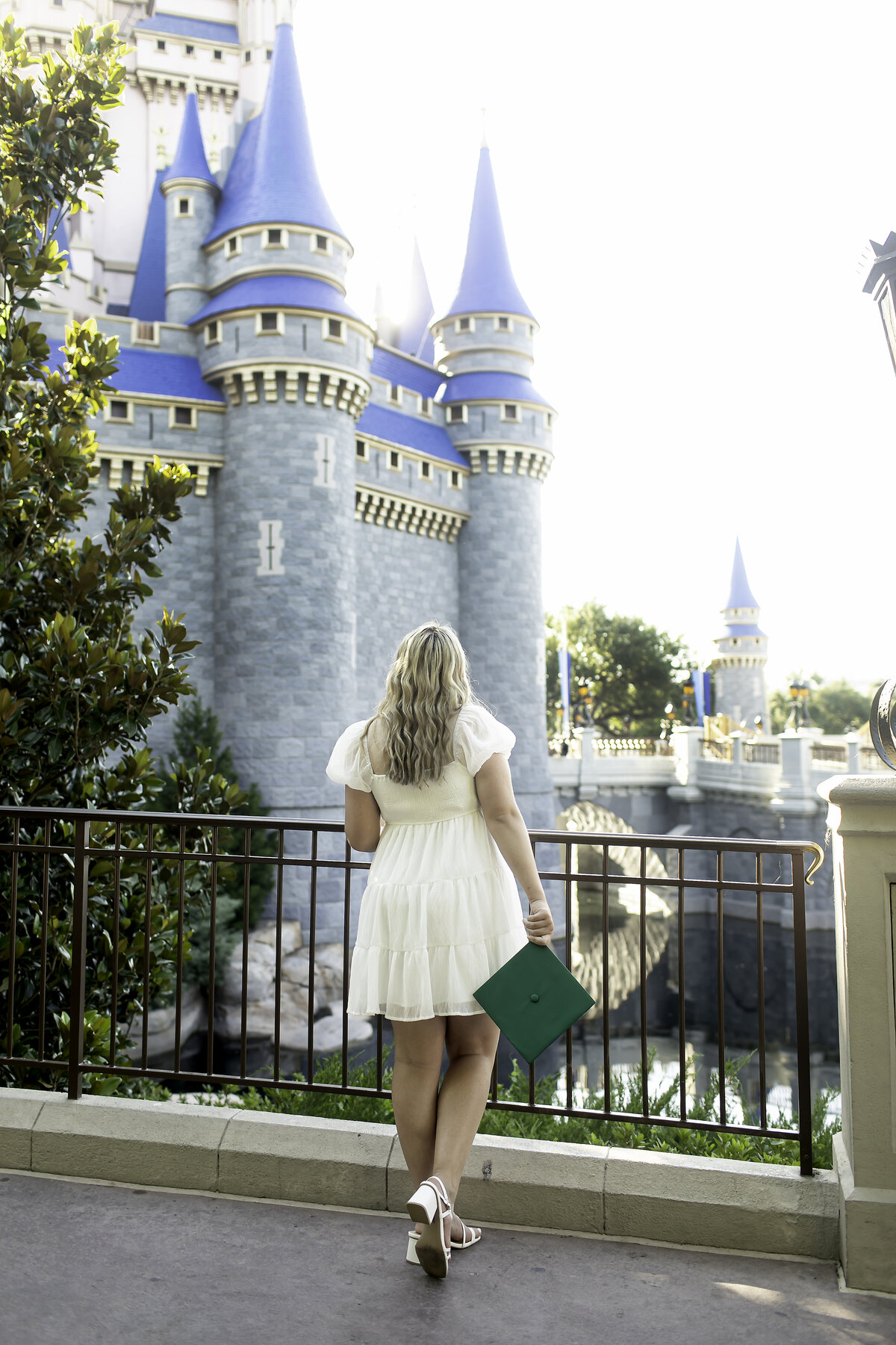 A high school senior holding their graduation cap and gazing up at the iconic Cinderella's Castle at Disney World, symbolizing the bright future ahead and the magic of their accomplishments.