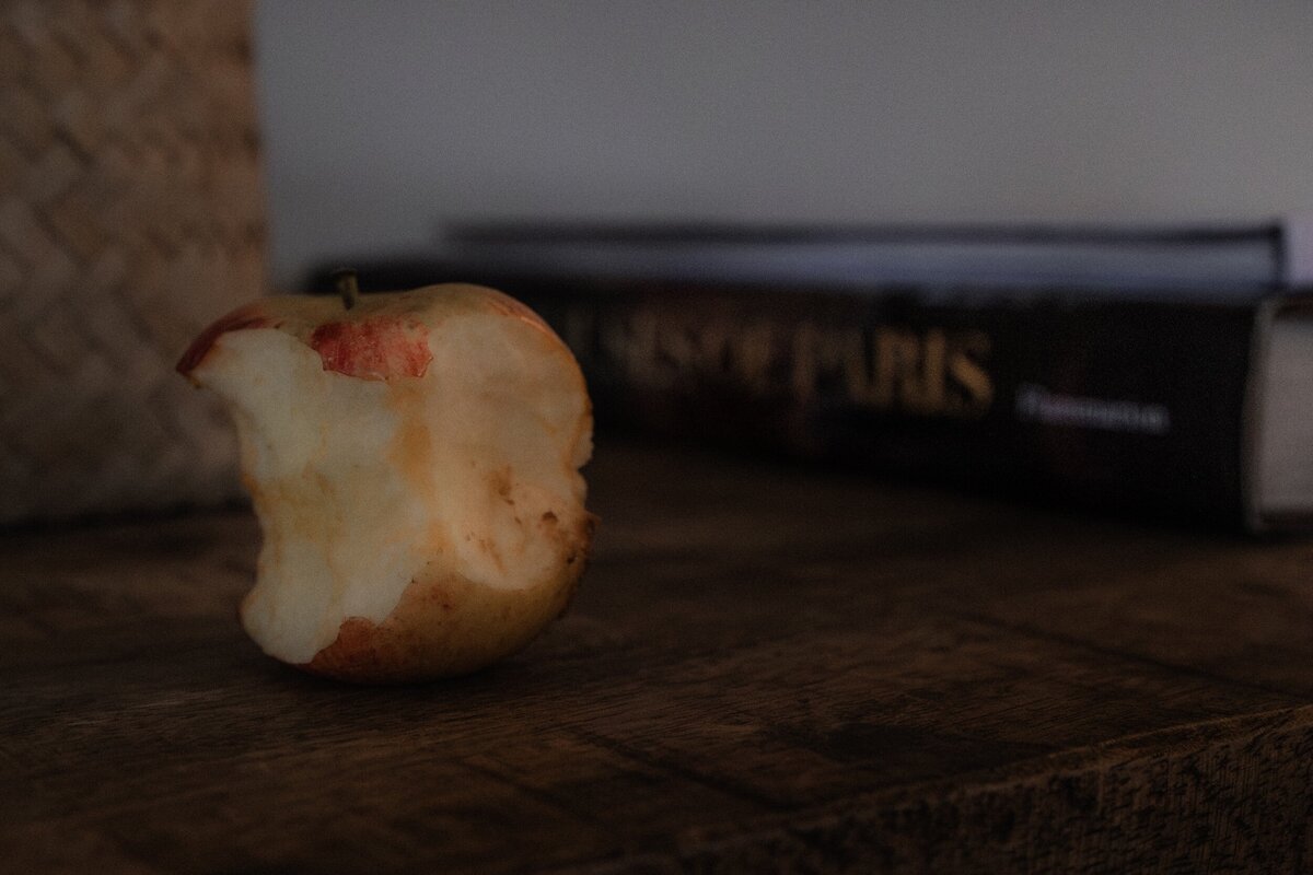 photograph of an half eaten apple beginning to brown, next to a book titled "Houses of Paris", part of The Quiet Gift series by Marie Kenny.