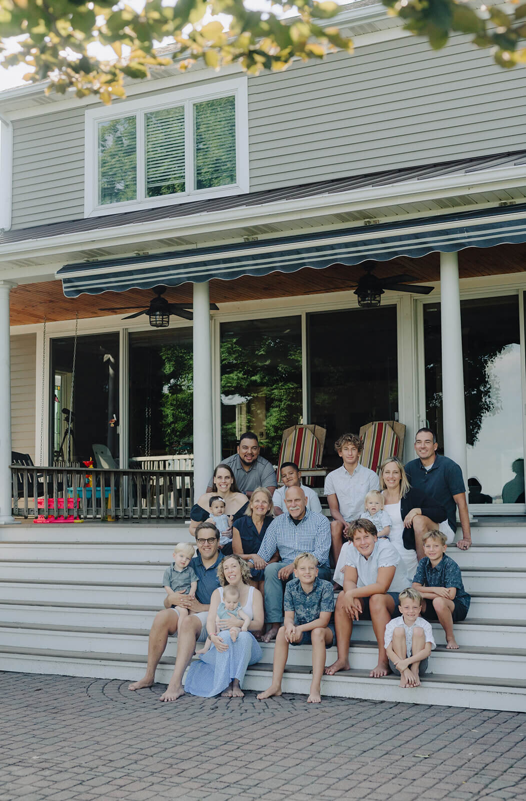 Family sitting on steps of house at generational photoshoot in Finger Lakes, NY