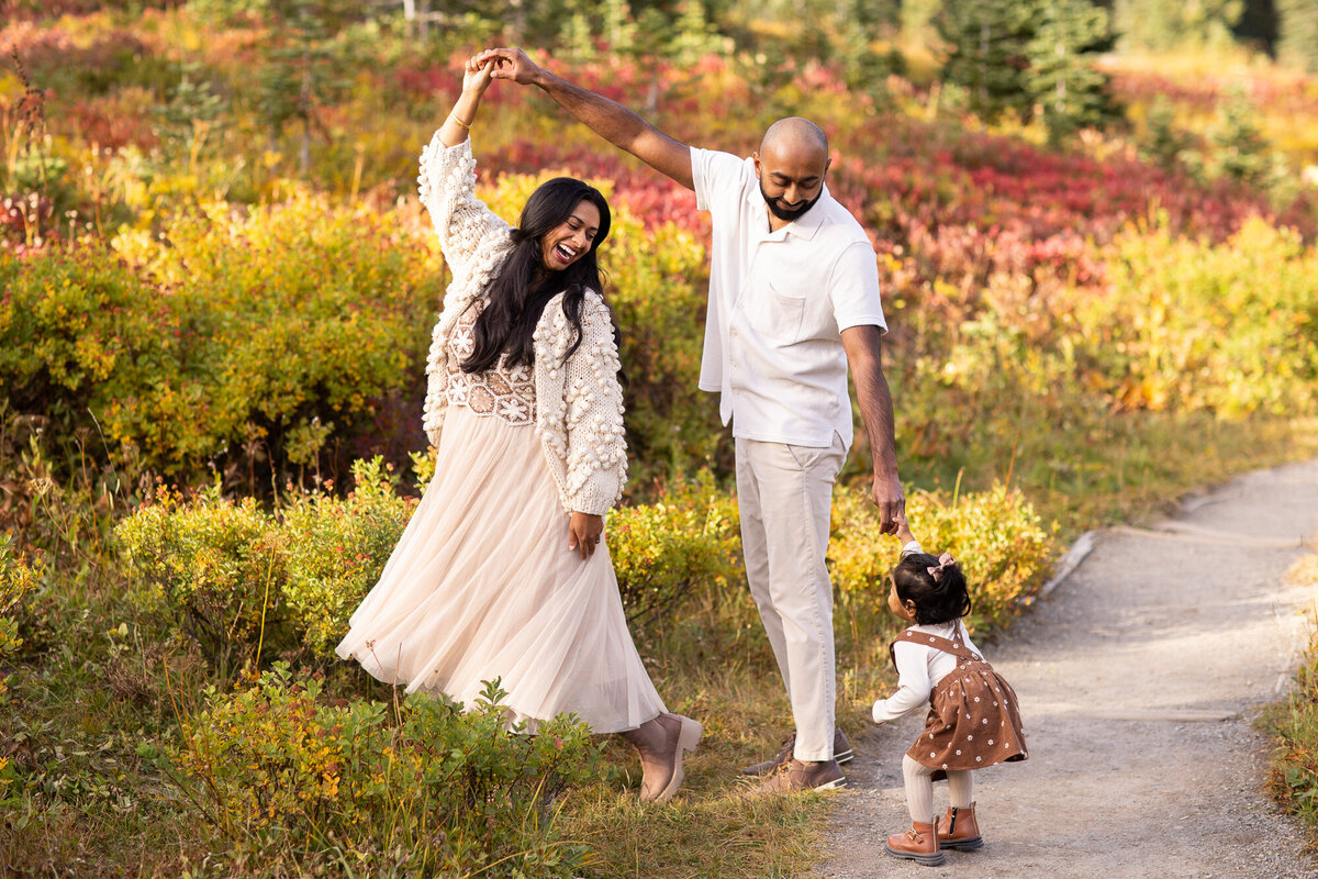 Family of three dancing in autumn colored pacific northwest landscape.