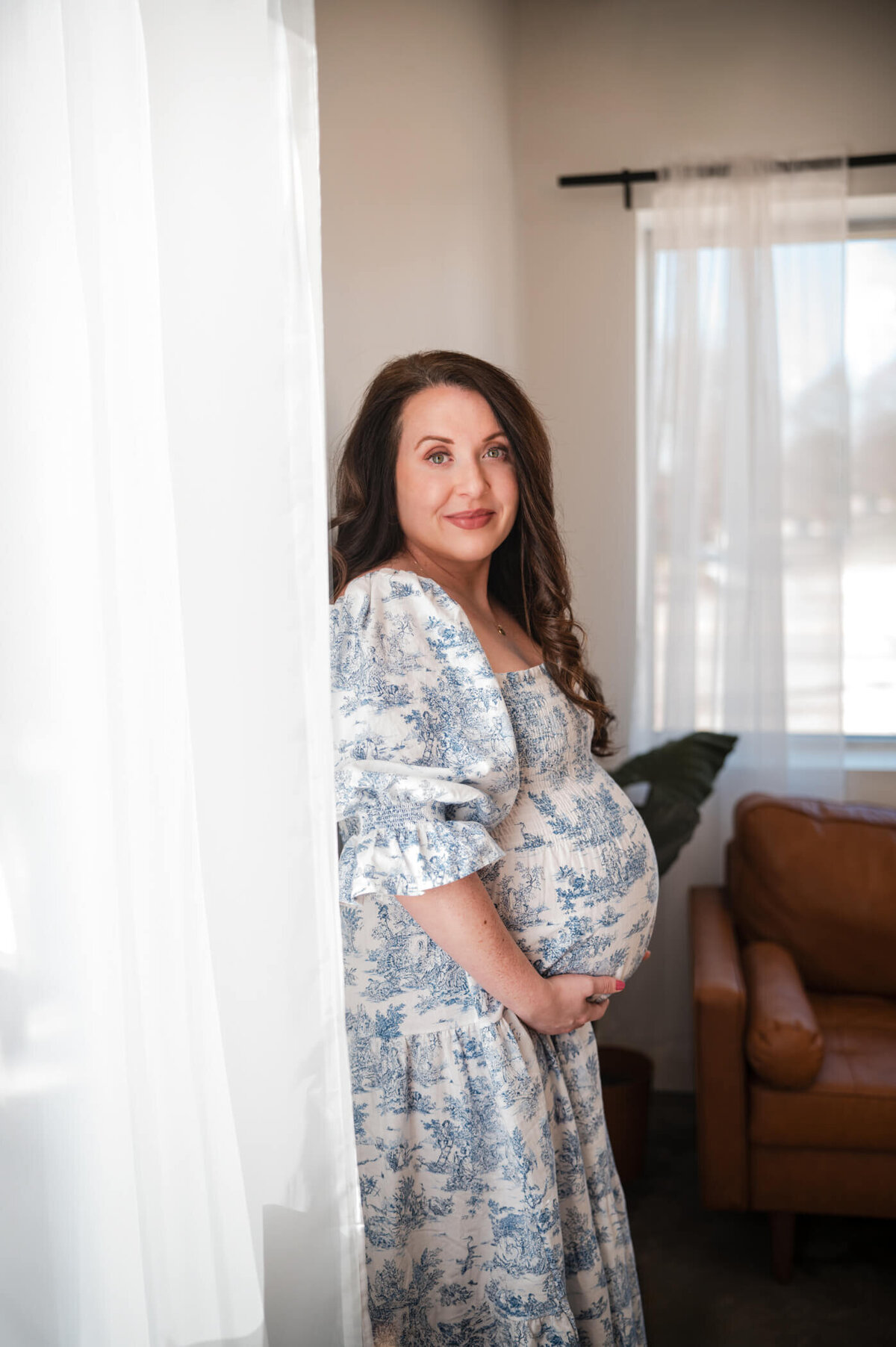pregnant model holding her belly wearing a nothing fits but dress that has a blue and white pattern on it