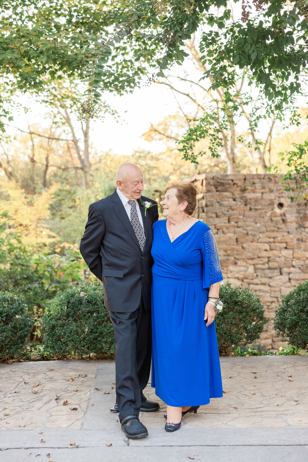 An older couple with their arms around each other smiling at each other