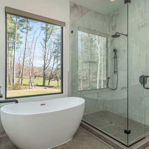 A bathroom with a glass shower and a large tub