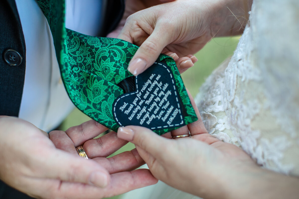 bride shows wedding photographer personalized message sewn into back of father's tie