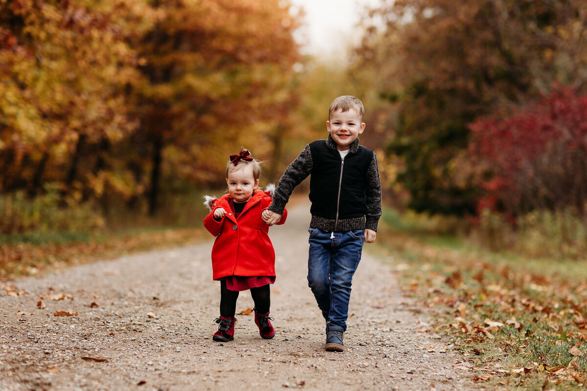 2 and 3 year old walking down dirth path in fall