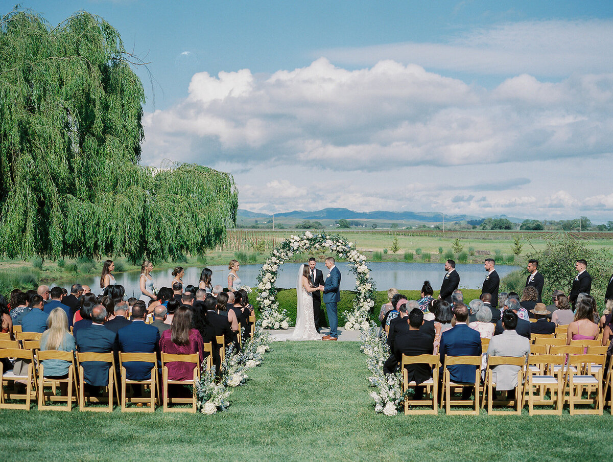 A beautiful outdoor setting wedding ceremony with the couple exchanging vows surrounded by family and friends.
