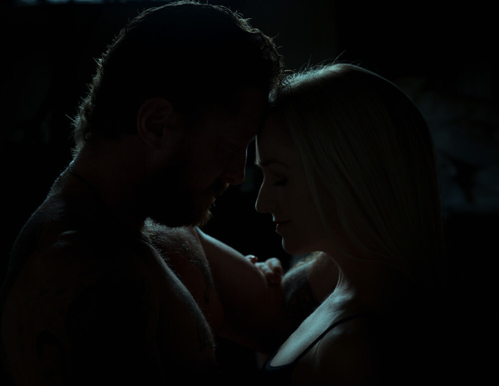 Two people with their heads in a heart shape lit by blue light.