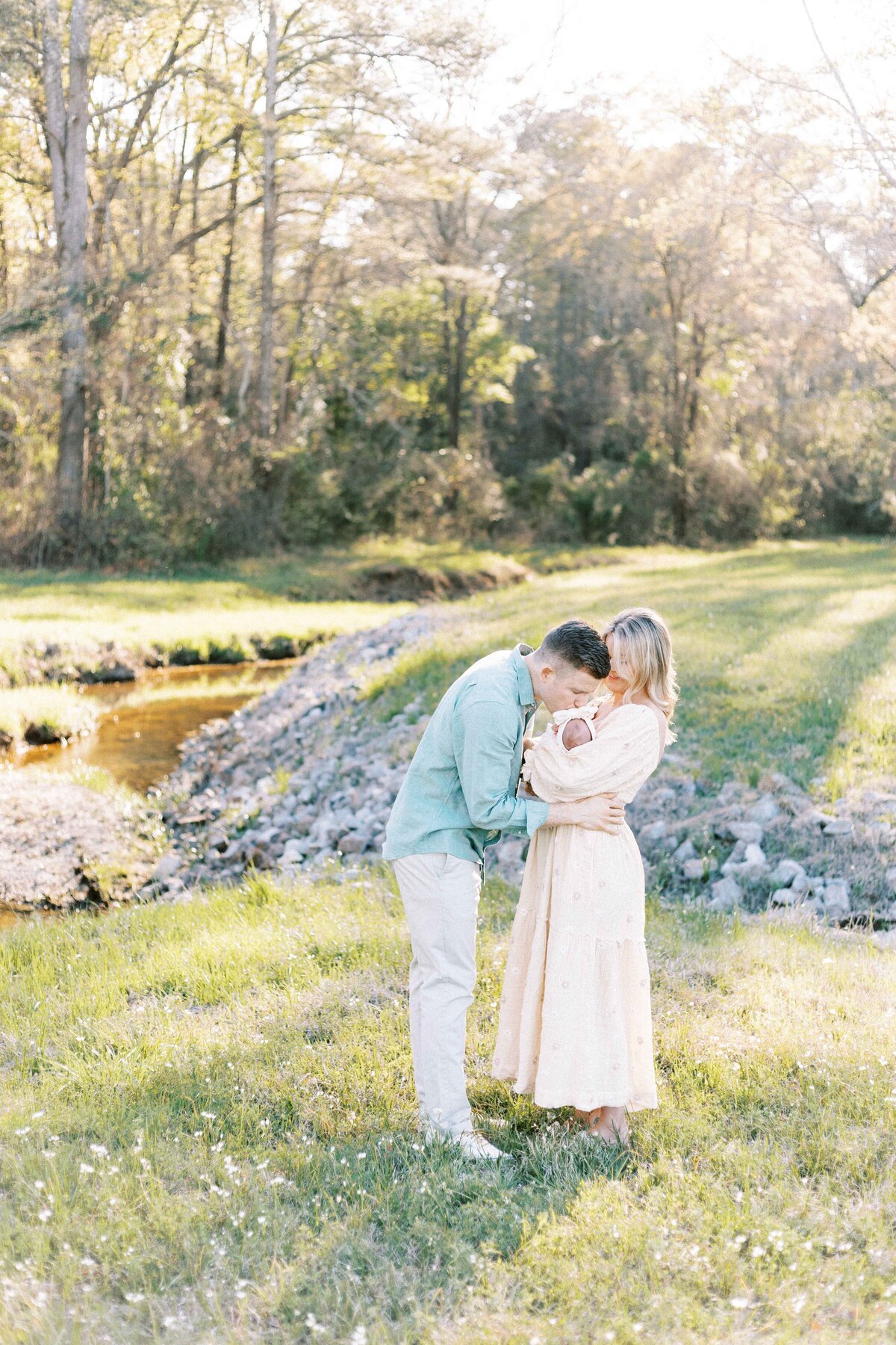 dad kissing newborn baby in outdoor peoria illinois newborn photos
