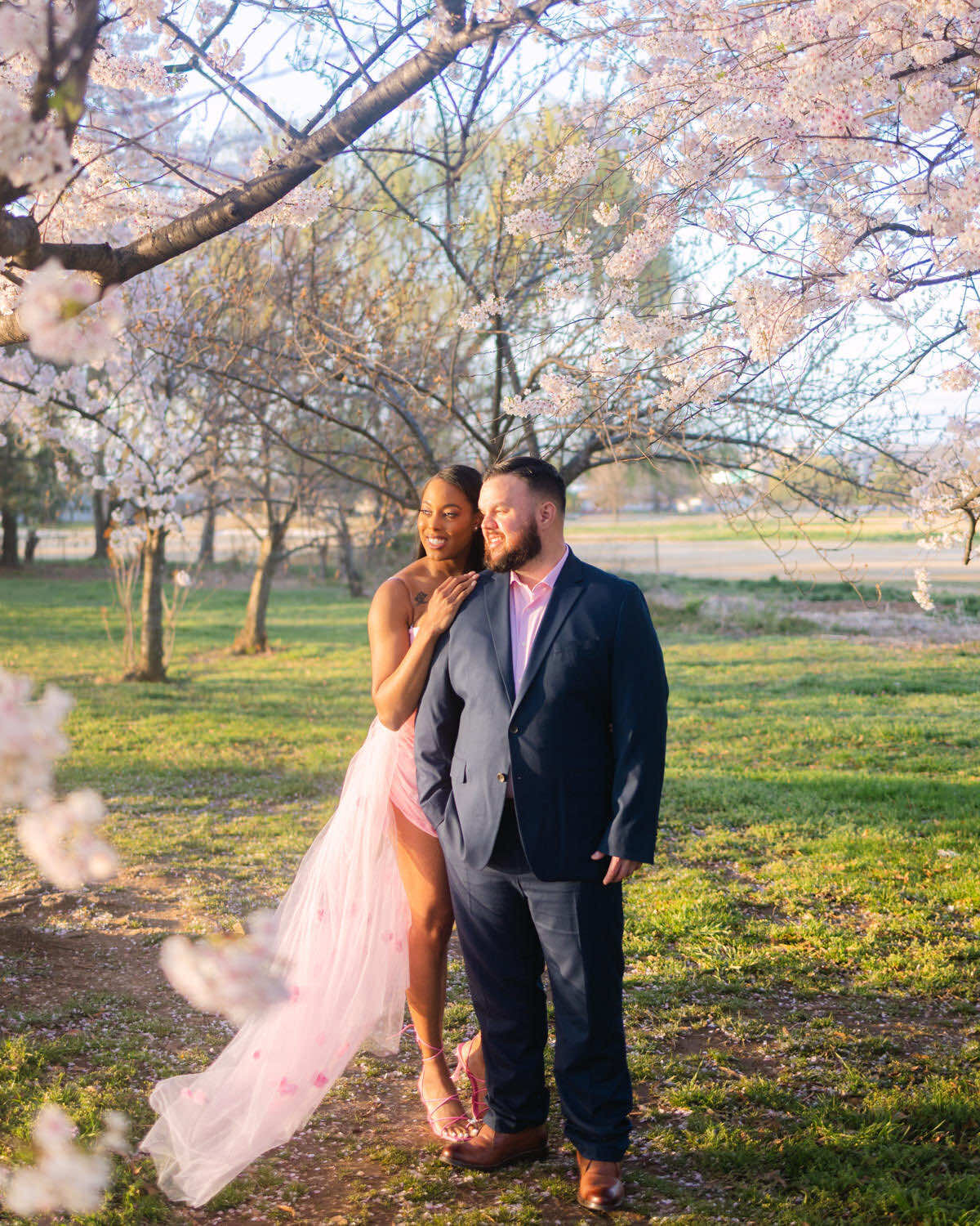 Couple is posing for their engagement photo surrounded by cherry blossom trees in Washington DC.