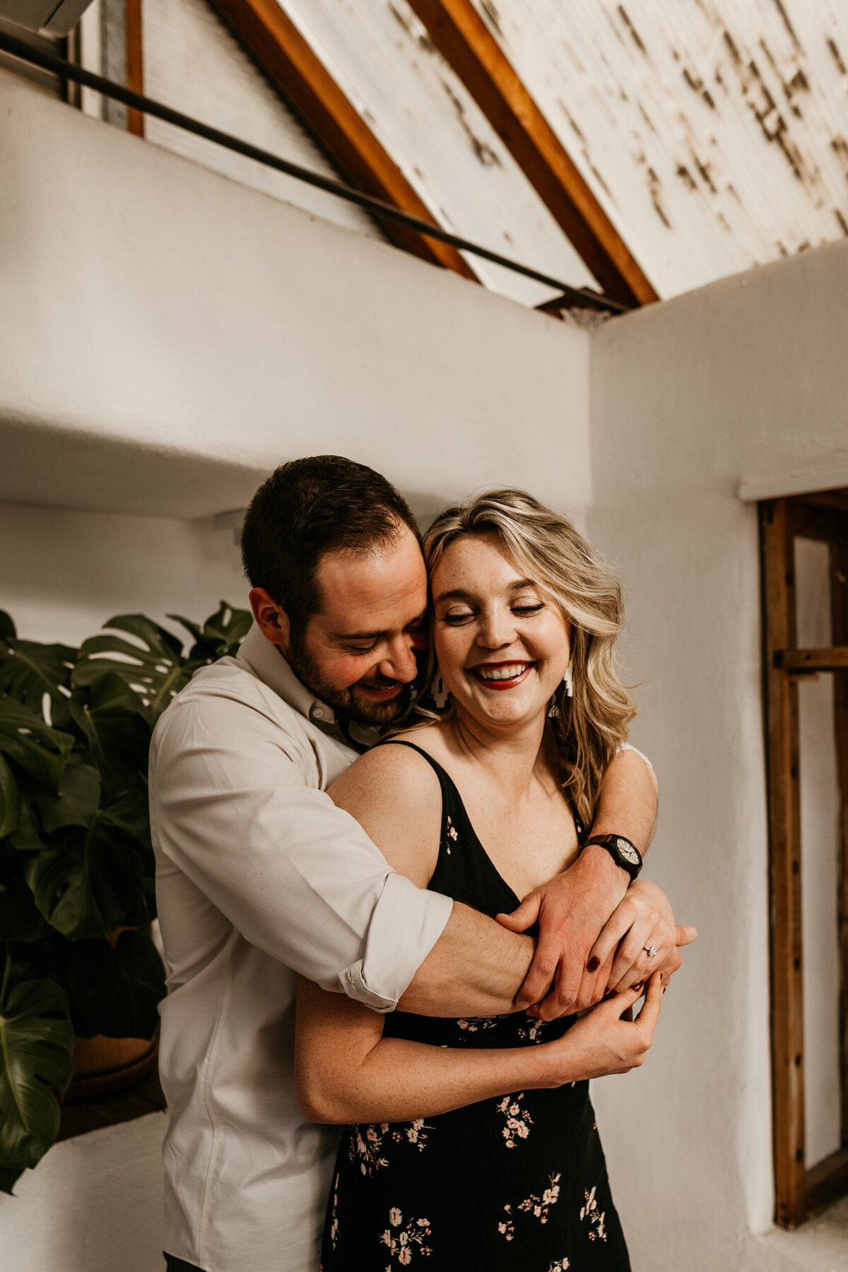 man hugging woman from behind in a greenhouse