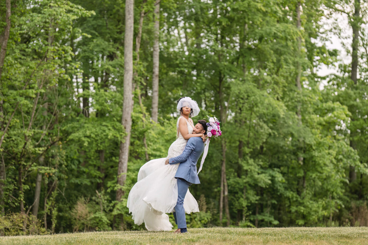 Dreamy outdoor wedding portrait of the bride and groom embracing in a lush green setting.