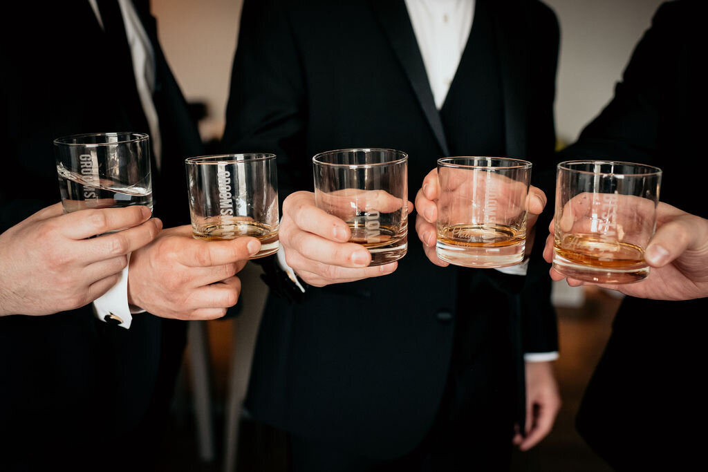 Close-up of groomsmen toasting with glasses of liquor at a spring wedding at the Palm Event Center in Pleasanton, CA.