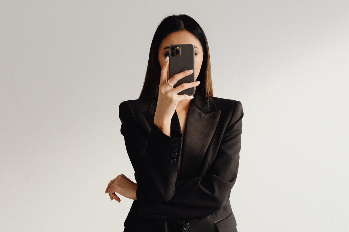 kaboompics_dark-classy-aesthetic-fashion-beautiful-asian-female-entrepreneur-in-black-suit-technology-and-devices-iphone-laptop-airpods-30098