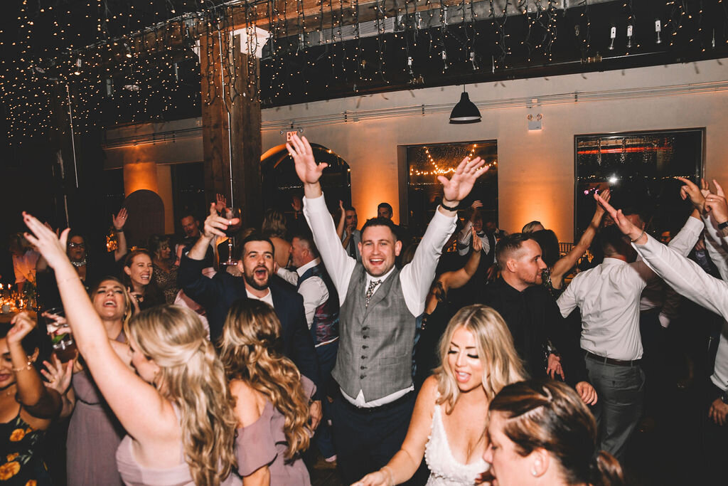 Packed dance floor and glowing lights at Liberty Warehouse wedding.

