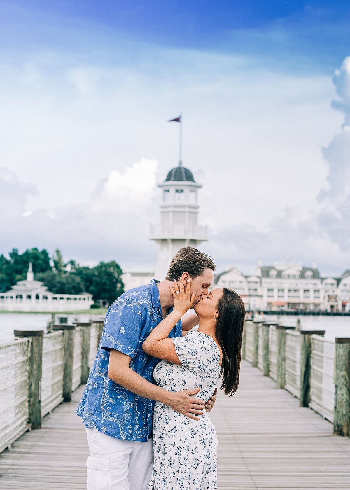 Newly engaged couple kiss in front of light house at Disney's Yacht and Beach Club