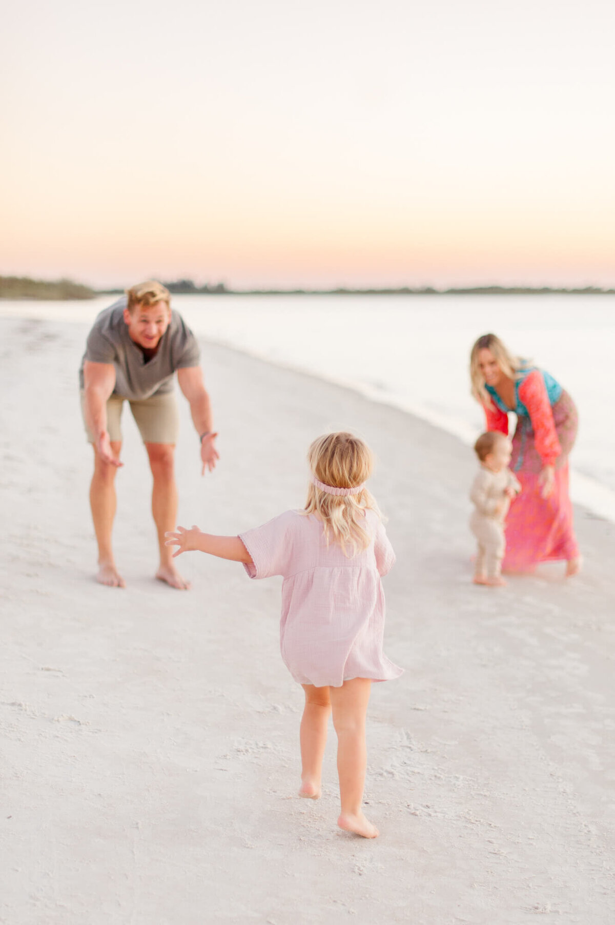 Action photo of a family playing with each other near the shoreline at sunset