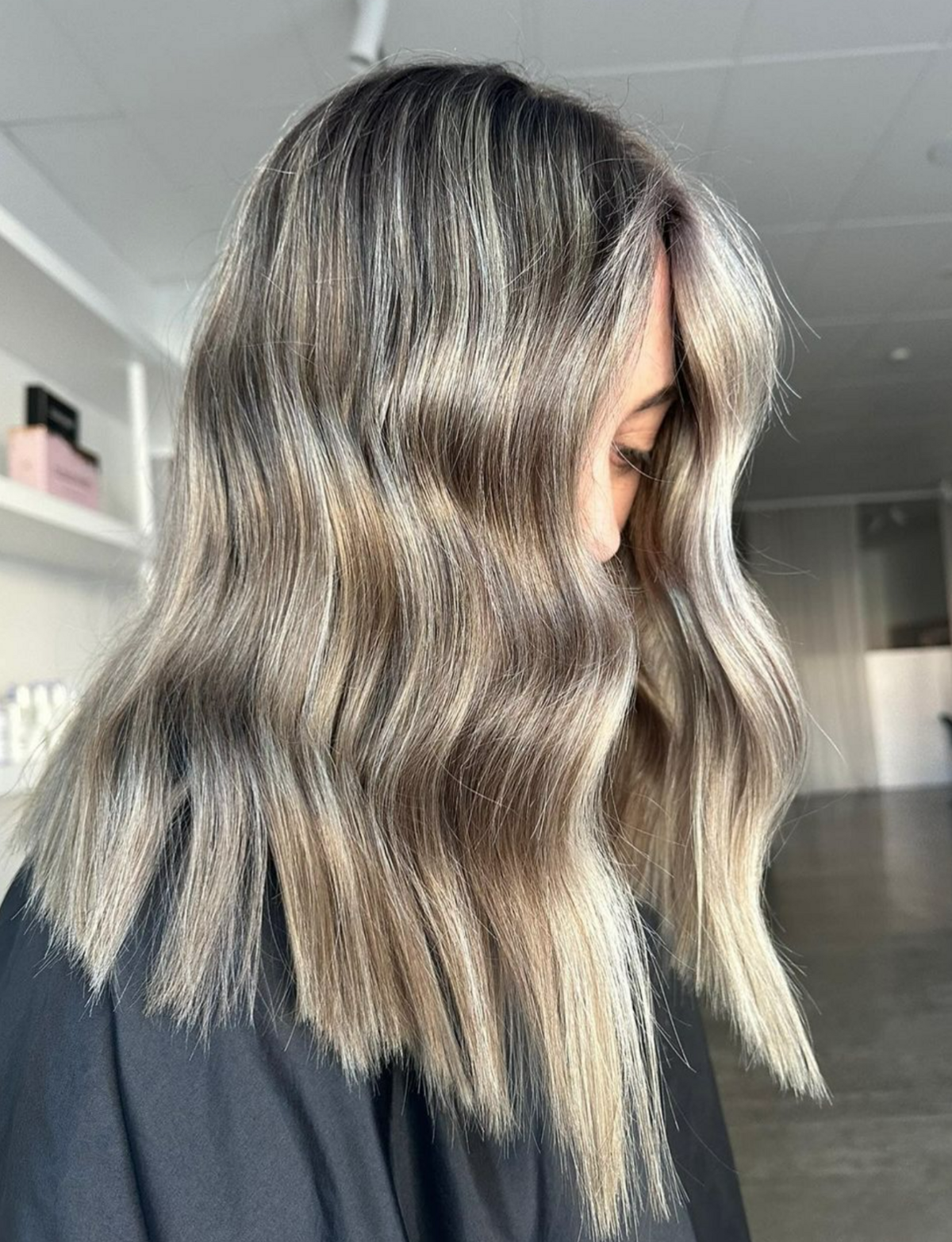 Woman I black hairdresser cape with freshly coloured hair - blonde foils