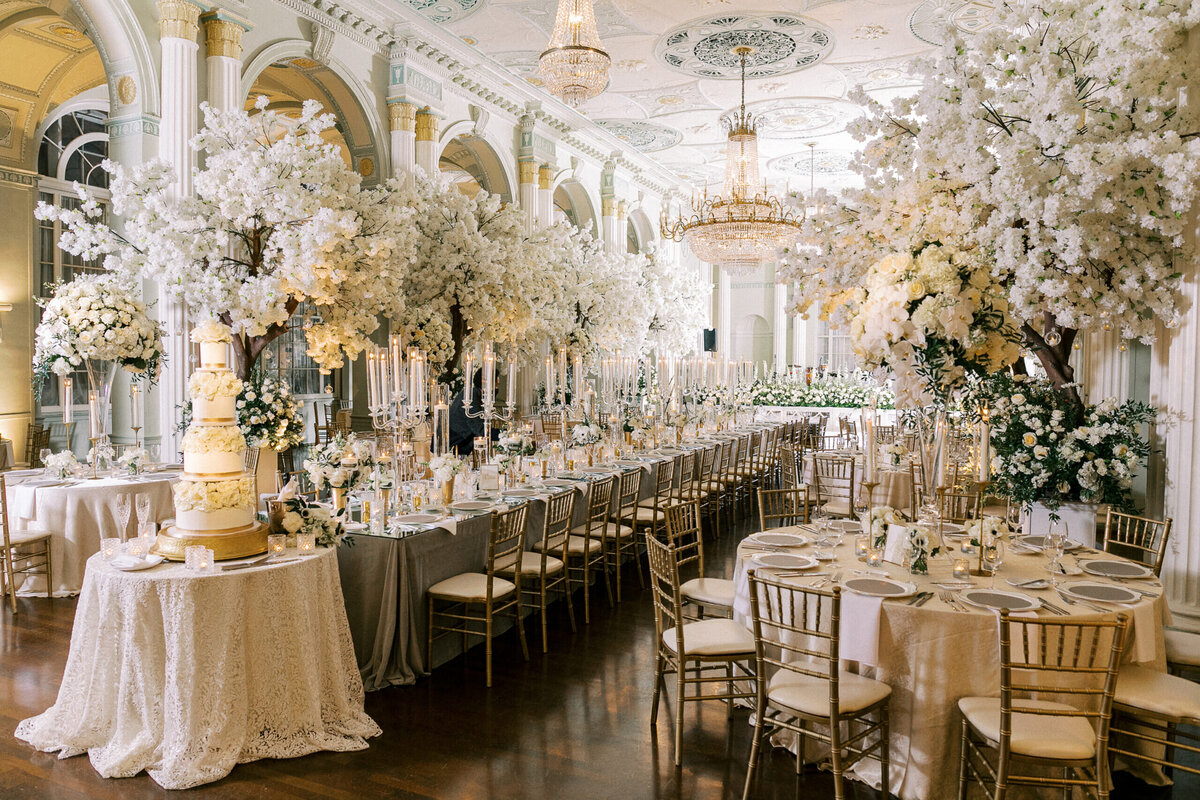 Grand and elegant wedding reception set up with long tables and large white flower bouquets in tall vases