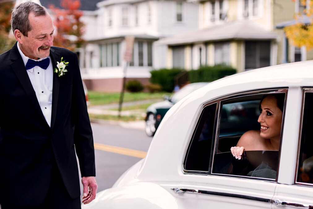 A dad looking at his daughter in a car before she gets married.
