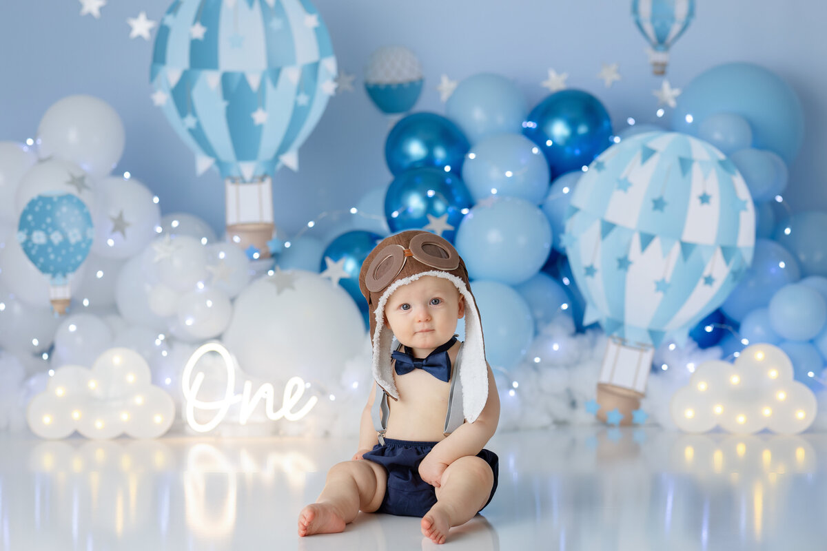 One year old Tampa baby enjoying a personalized luxury cake smash session with hot air balloon decorations