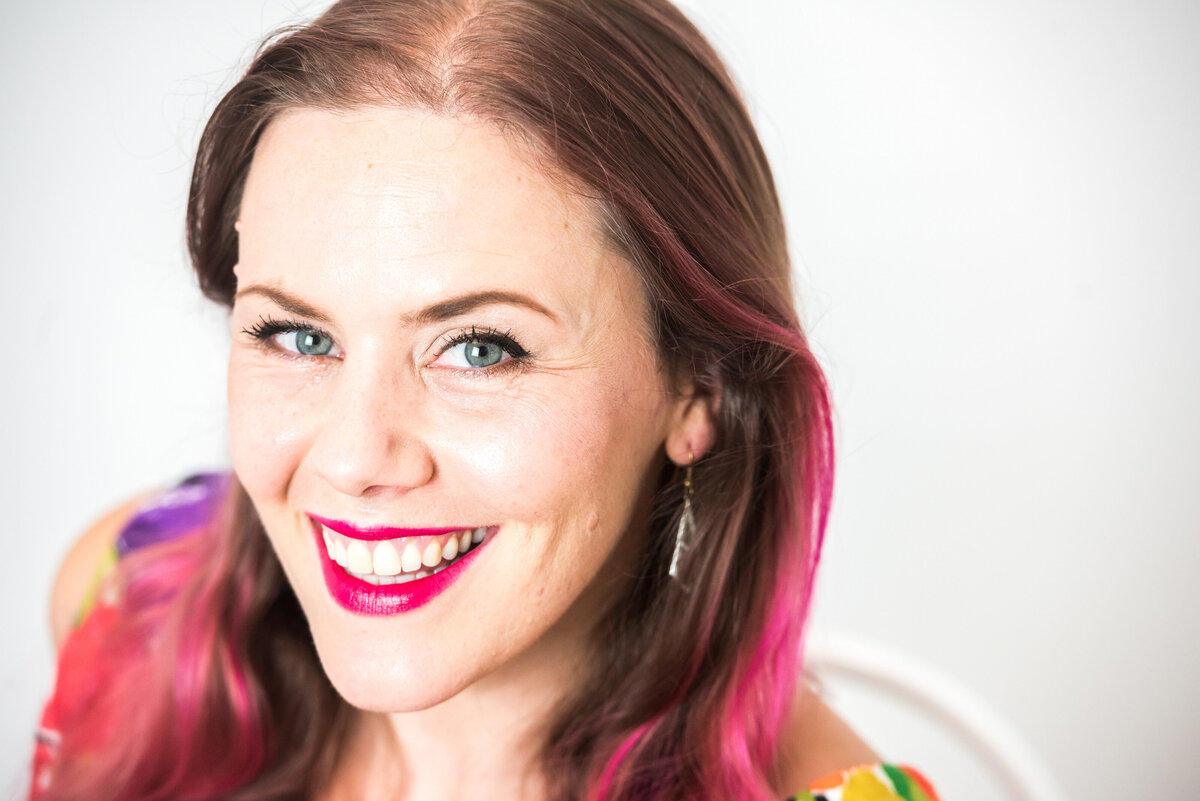 A woman with a pink streak in her hair smiling