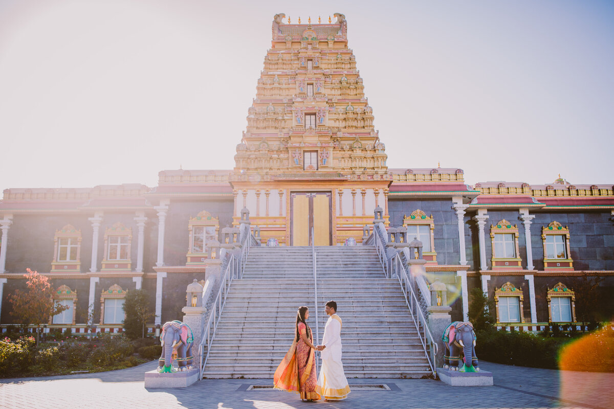 A couple in south indian outfits standing in front of the sri guruvaayoorappan hindu temple in morganville nj