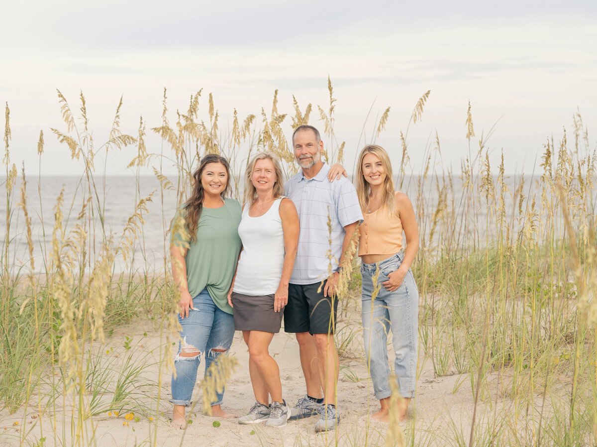 family beach photo shoot near the dunes on the beach standing in tall grass