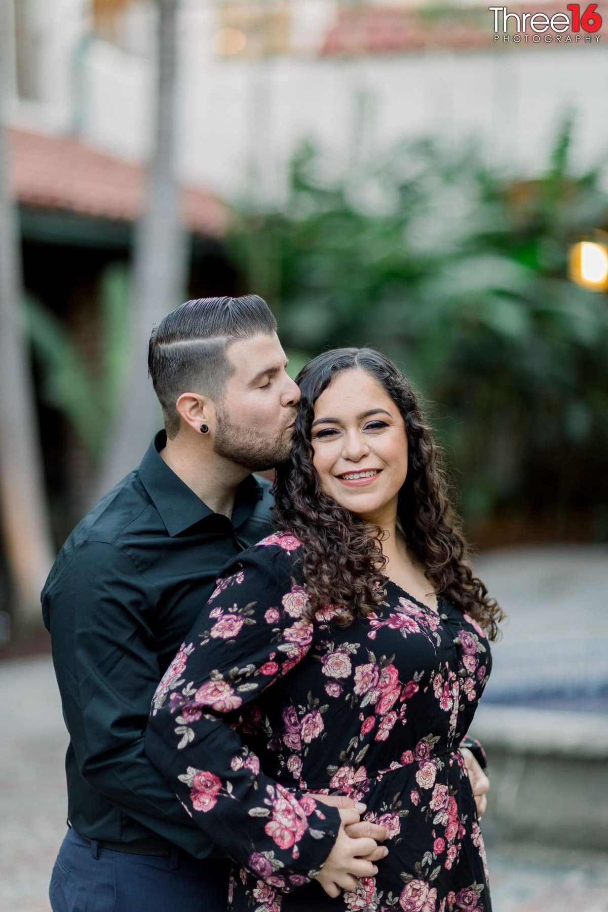 Groom to be kisses his Bride's head  as they lock fingers