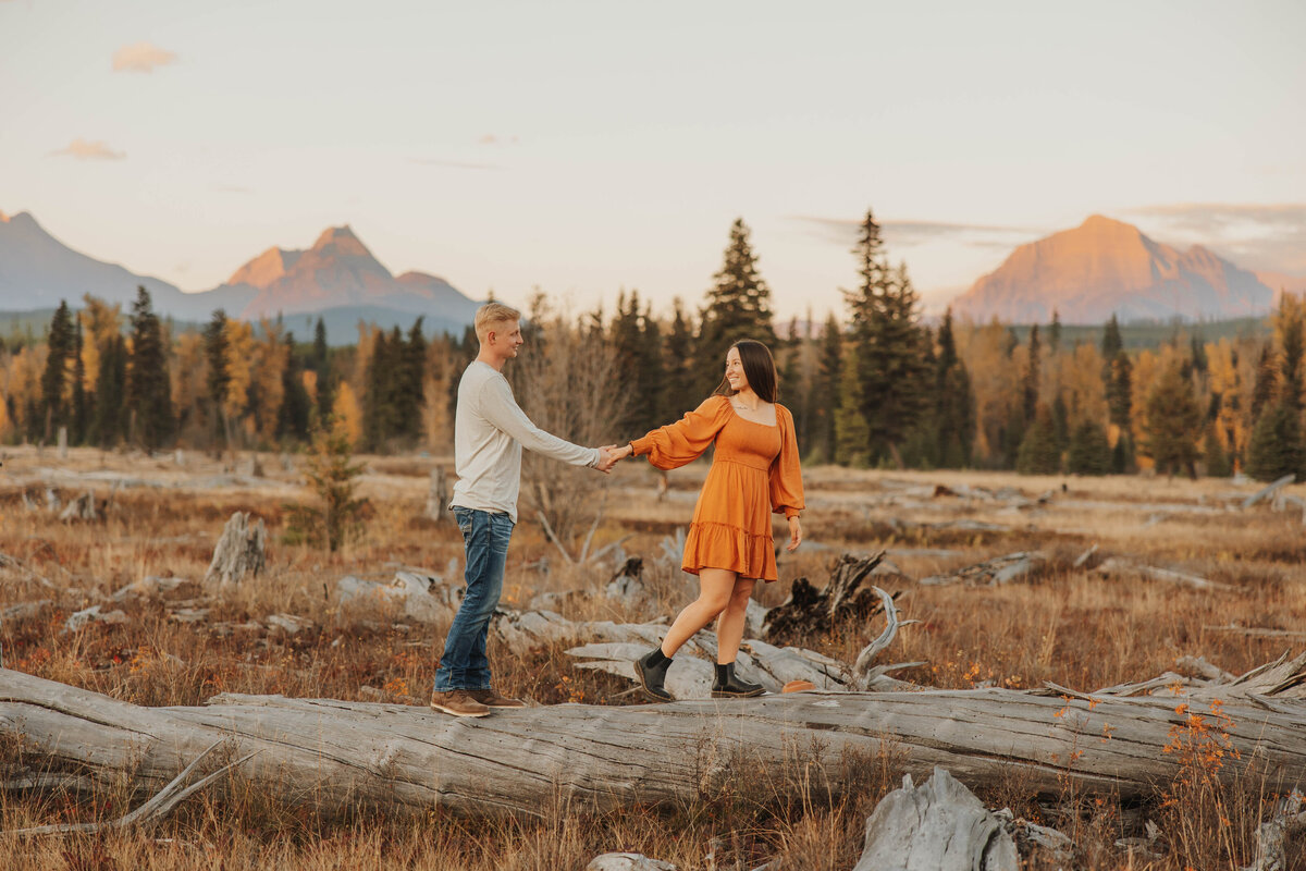 couple holding hands on log