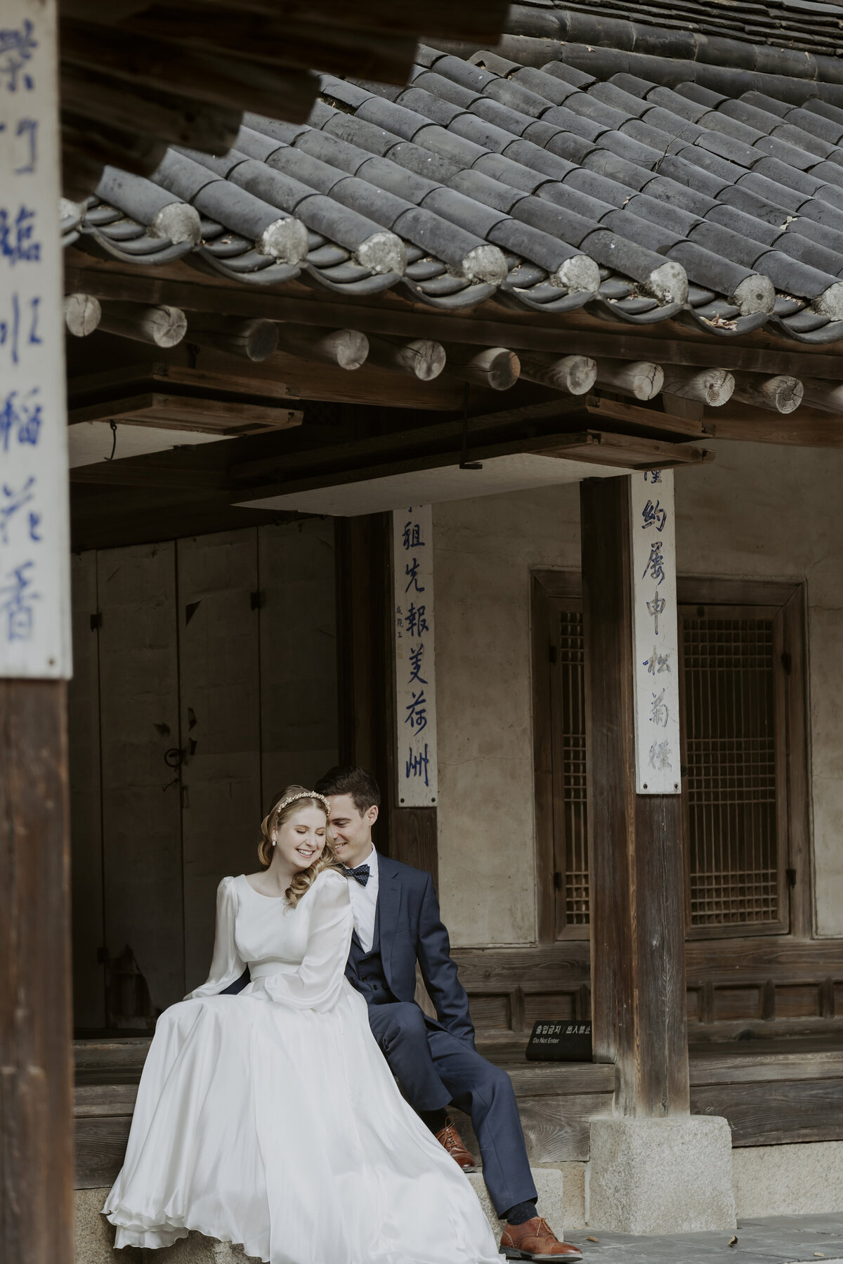 a candid moment of the couple sitting outside a korean old house