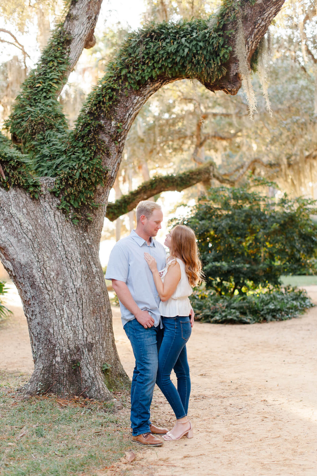 Couple poses next to a tree while staring lovingly at each other at Washington Oaks Gardens State Park