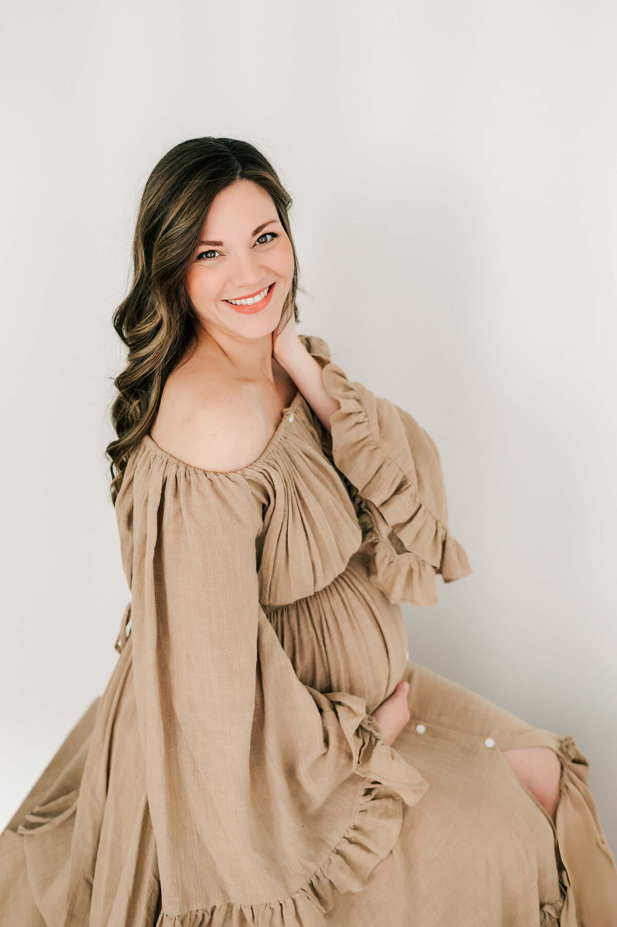 pregnant mom in brown dress smiling in Springfield MO maternity photography studio