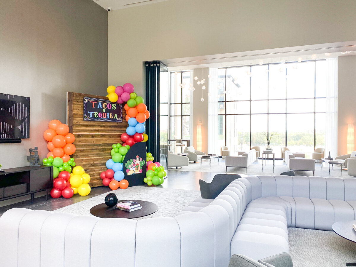 Colorful tacos and tequila wooden backdrop design with balloon arches for corporate event