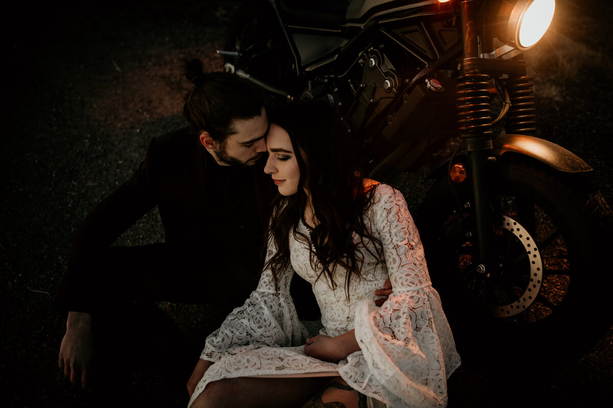 bride and groom sitting against a motorcycle at night