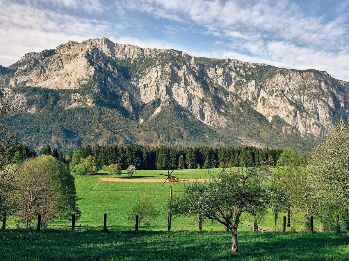 Frühlingsblick auf den markanten Dobratsch in Kärnten mit blühenden Obstbäumen im Vordergrund – professionelle Landschaftsfotografie vom Fotograf Atelier Schulte. Spezialist für Alpenlandschaften und Panoramafotografie in ganz Österreich.