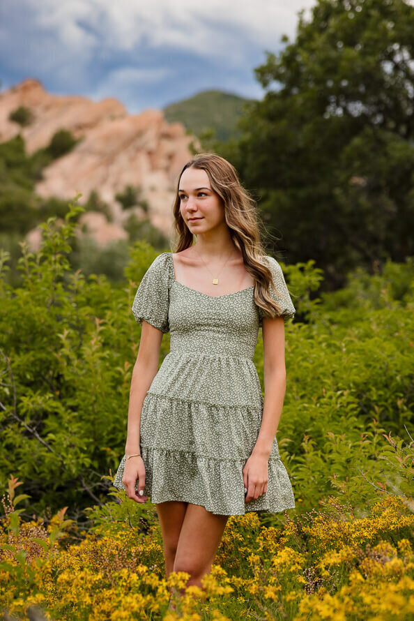 Girl in green dress looks off to side during her senior photos.