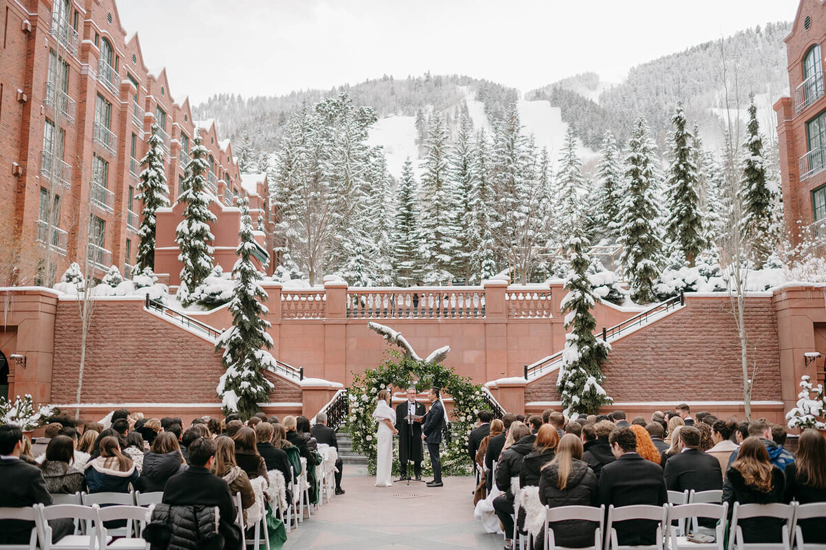 Wide shot image of the St. Regis outdoor  winter wedding ceremony with guests and bride and groom at the altar.