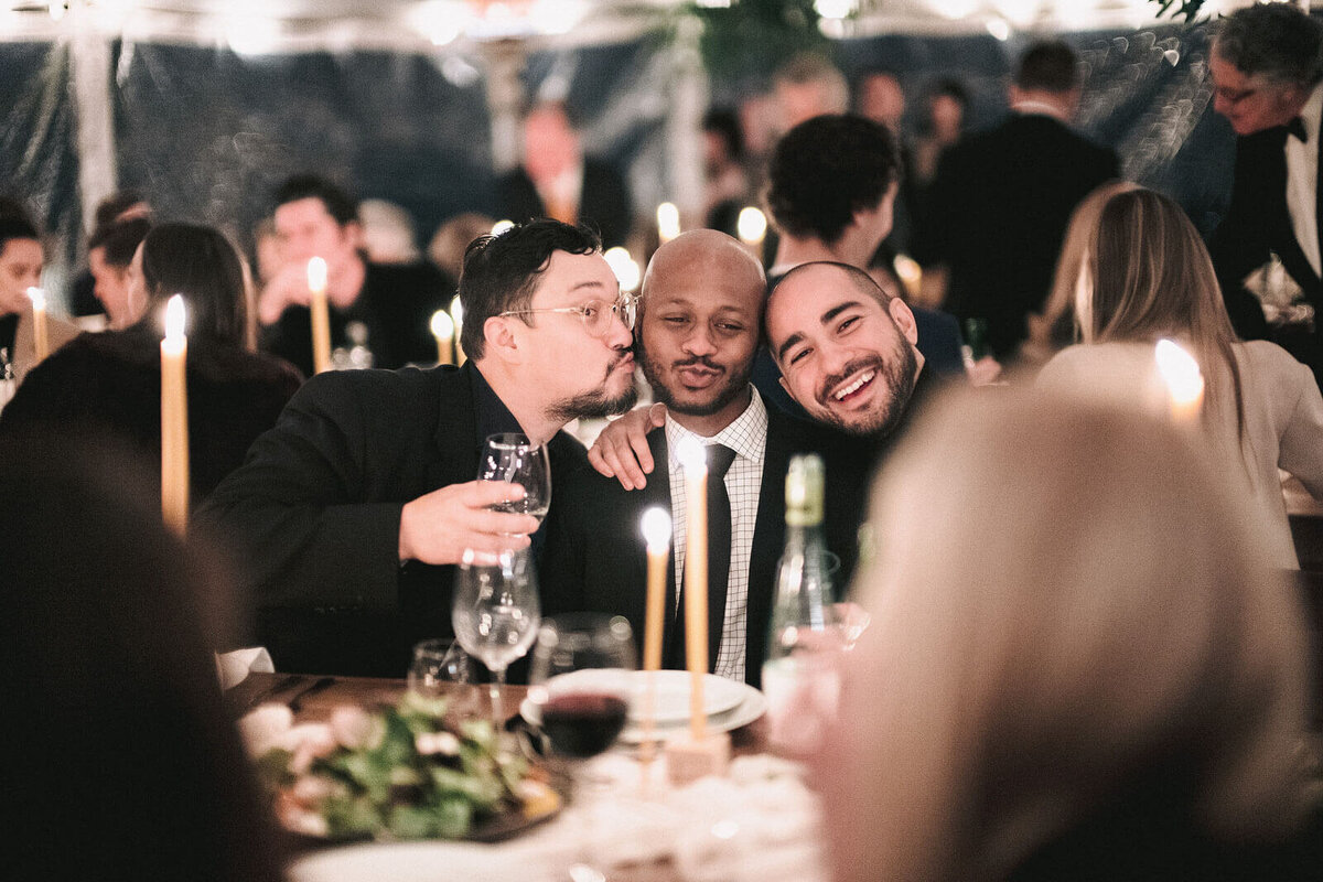 Three men guests jokingly pose for a photo in the reception in Foxfire Mountain House, New York. Wedding Image by Jenny Fu Studio