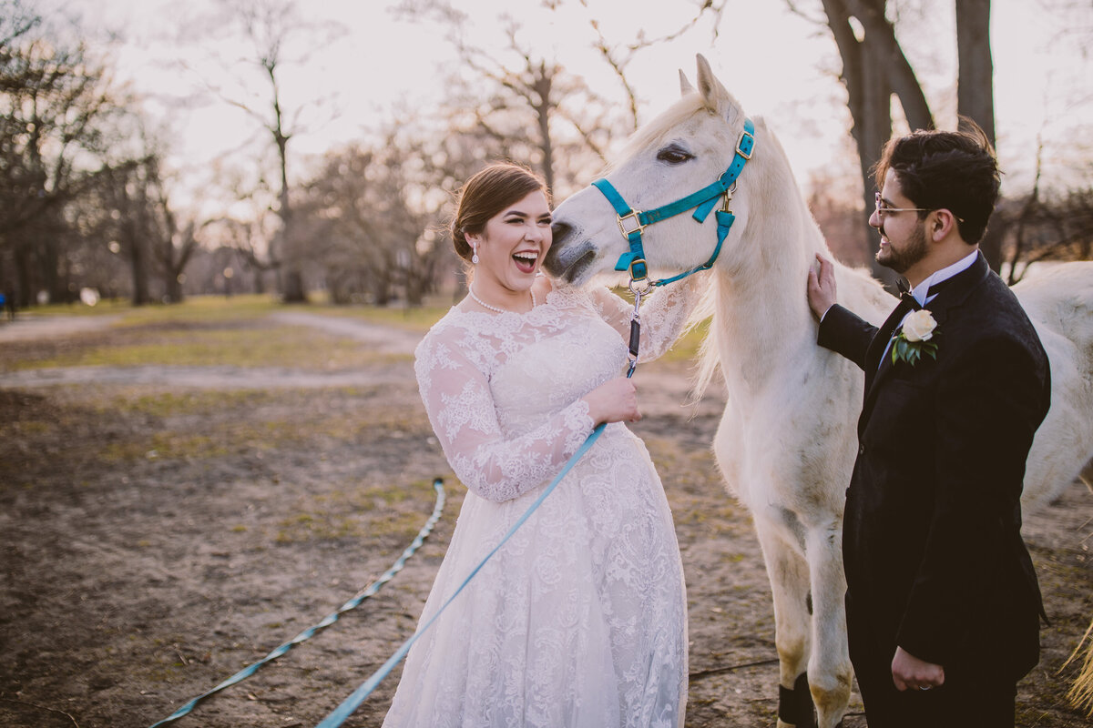 A horse nuzzling against a laughing egyptian arab bride on their wedding day at prospect park in brooklyn
