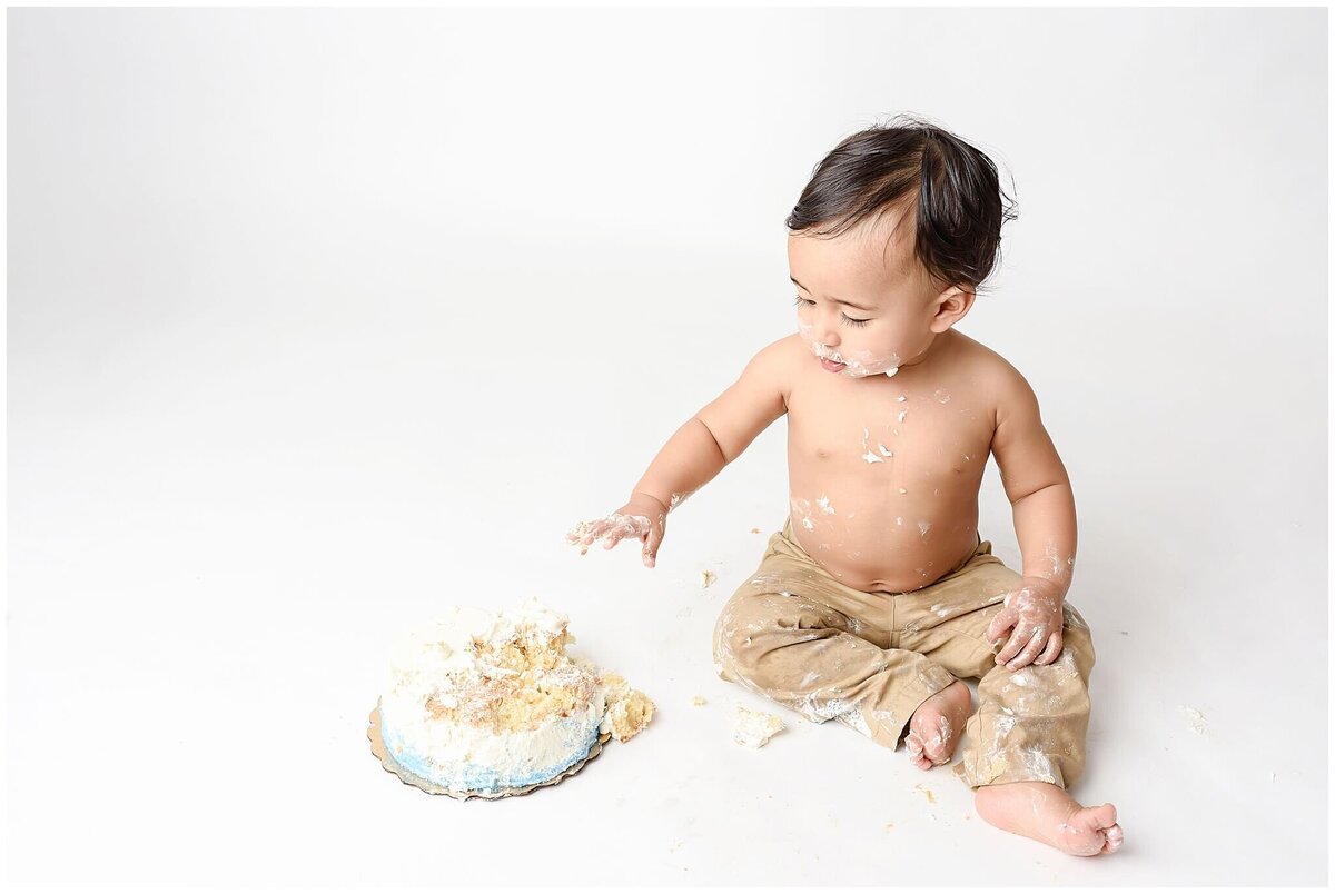 A messy cake smash session with a little one covered in frosting and giggling.
