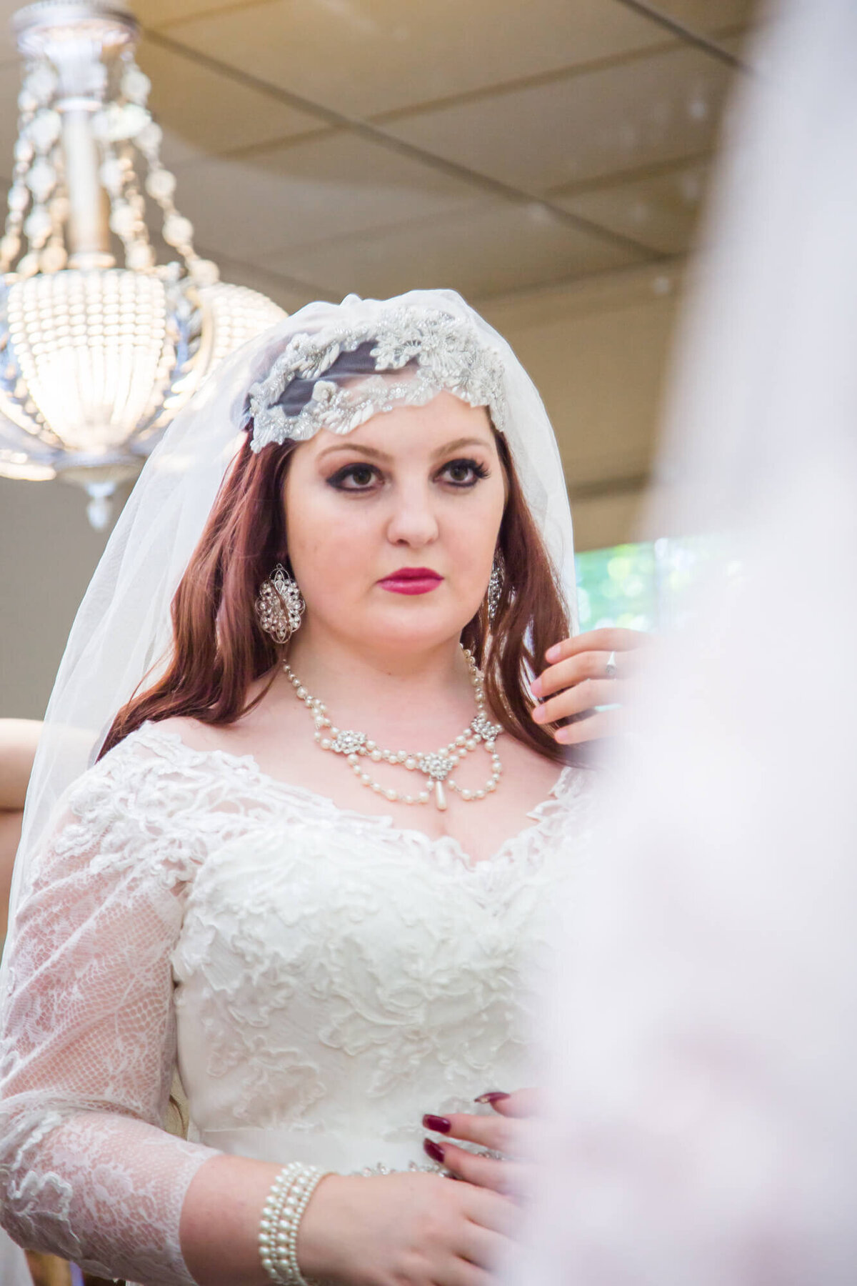 bride preparing for her beautiful garden wedding  by looking at her dress, makeup, and hair in the mirror