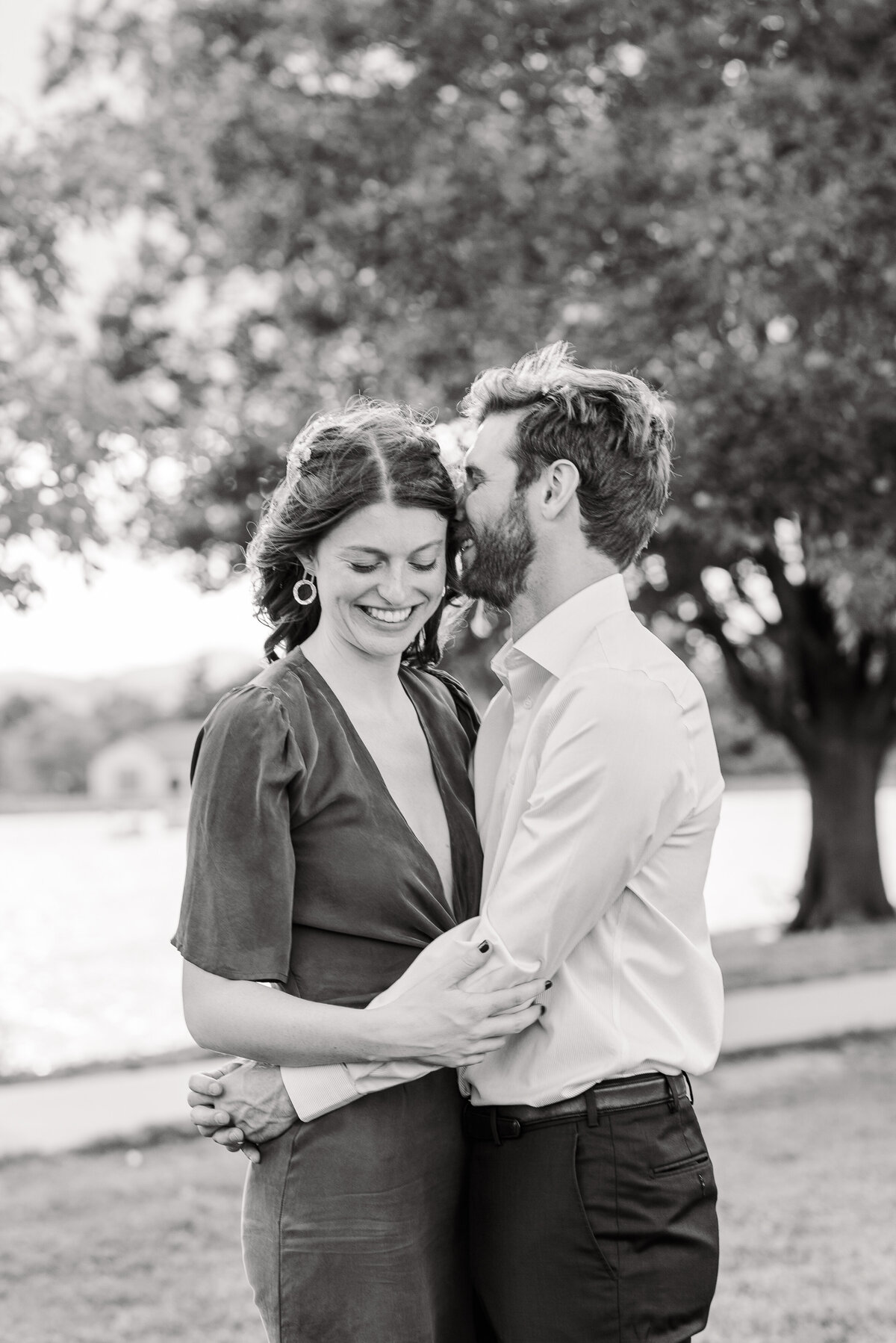 A man and woman wrap their arms around each other while the man whispers in the woman's ear and she looks down, captured by Denver wedding photographer, KB Radiant Photography