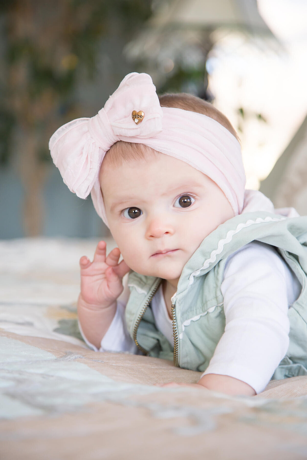 Stylish Infant baby girl  with poignant look on her tummy on a bed